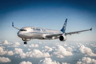 Avion de ligne moderne en vol au-dessus des nuages, vu en contre-plongée sous un ciel bleu profond